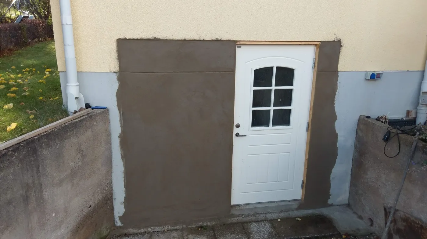 Putsad och slätad sockel runt en ny källardörr