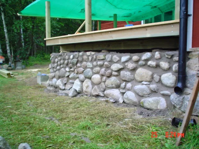 Mur av natursten som bär upp en nybyggd altan