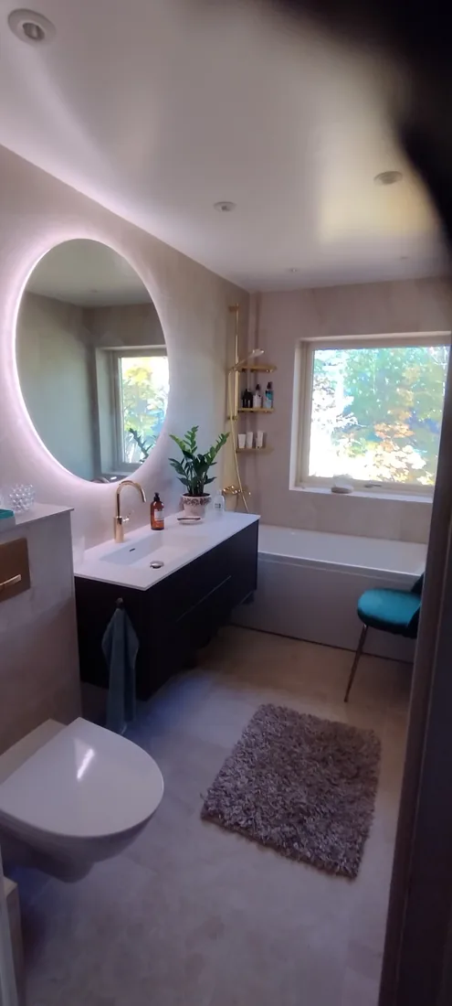 Badrumsrenovering med rund spegel utförd av Robert’s Hantverks Service