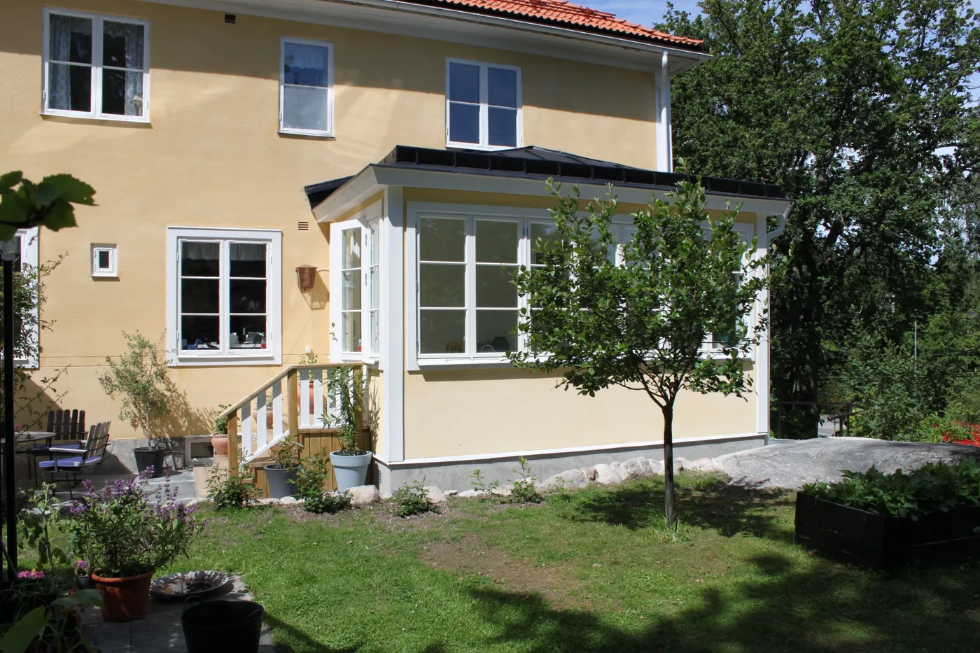 Glasverandan sedd från trädgården en sommardag