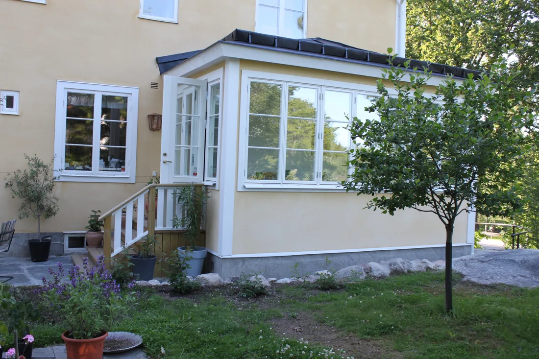 Färdig glasveranda med vitmålade fönsterpartier på gul putsad villa i Djursholm
